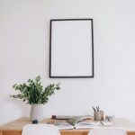 Stylish minimalist home office space with a blank frame, desk, and plant for creative inspiration.