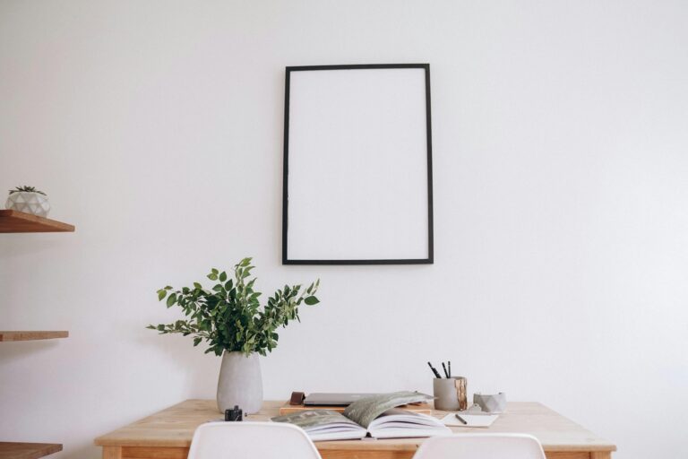 Stylish minimalist home office space with a blank frame, desk, and plant for creative inspiration.